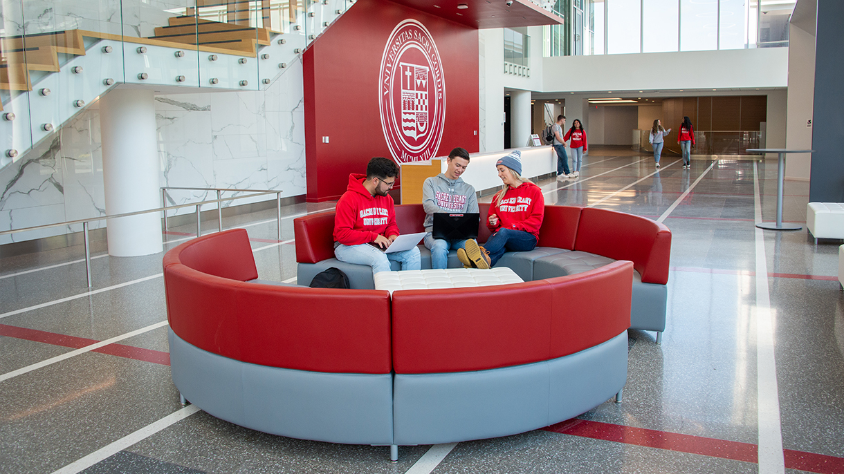 students sitting on a couch at the Sacred Heart University West Campus east building atrium