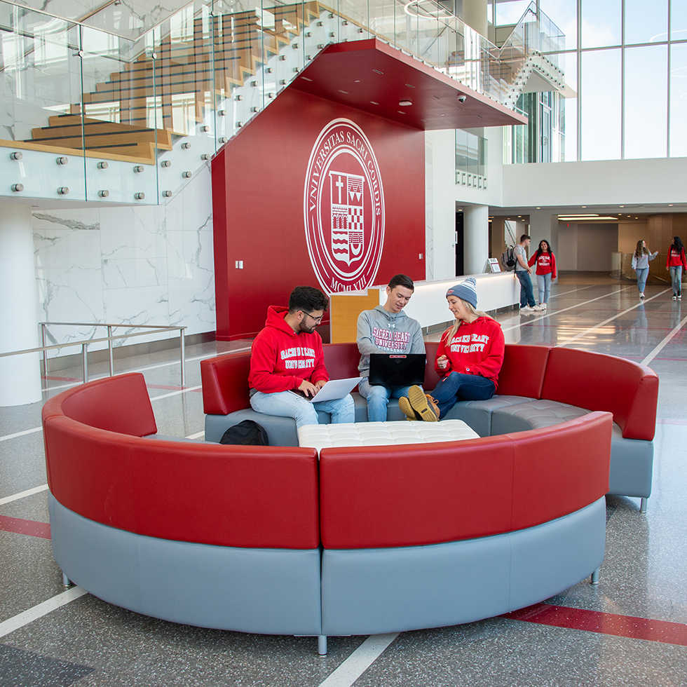 students sitting on a couch at the Sacred Heart University West Campus east building atrium