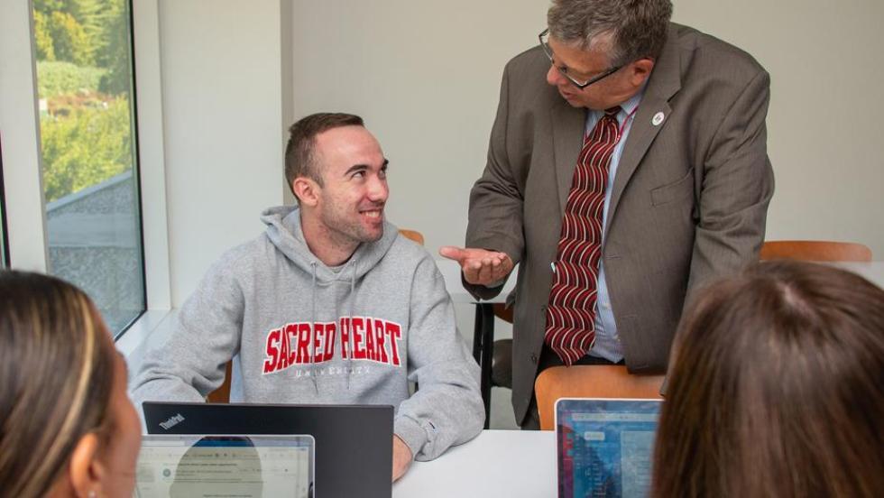 Students talking to professor in classroom