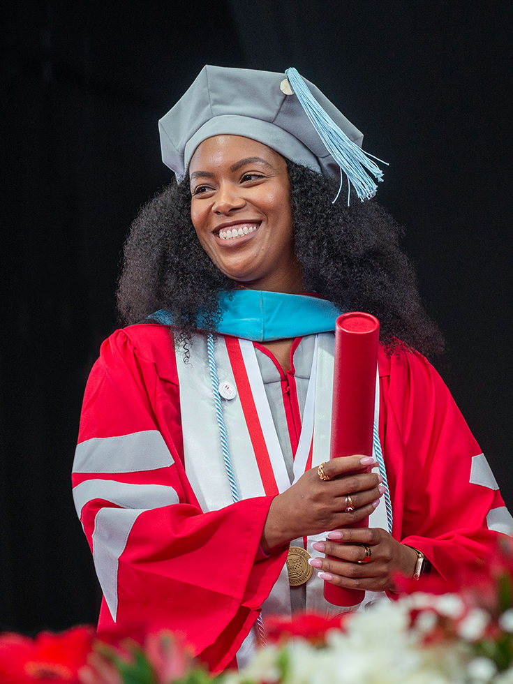 A smiling doctoral student getting their degree