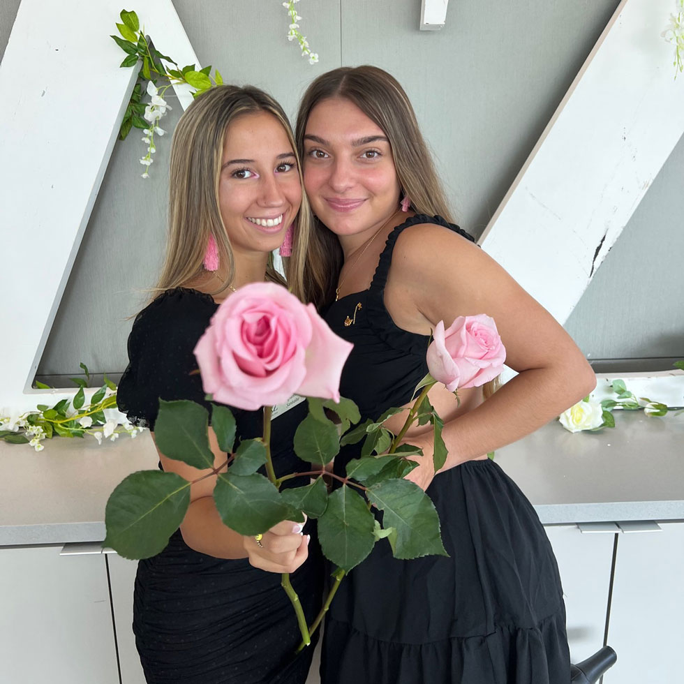 Delta Zeta members during recruitment holding pink flowers, wearing black dresses
