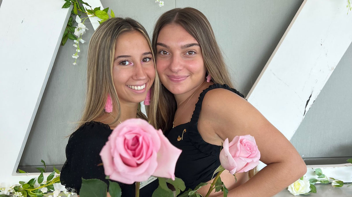 Delta Zeta members during recruitment holding pink flowers, wearing black dresses