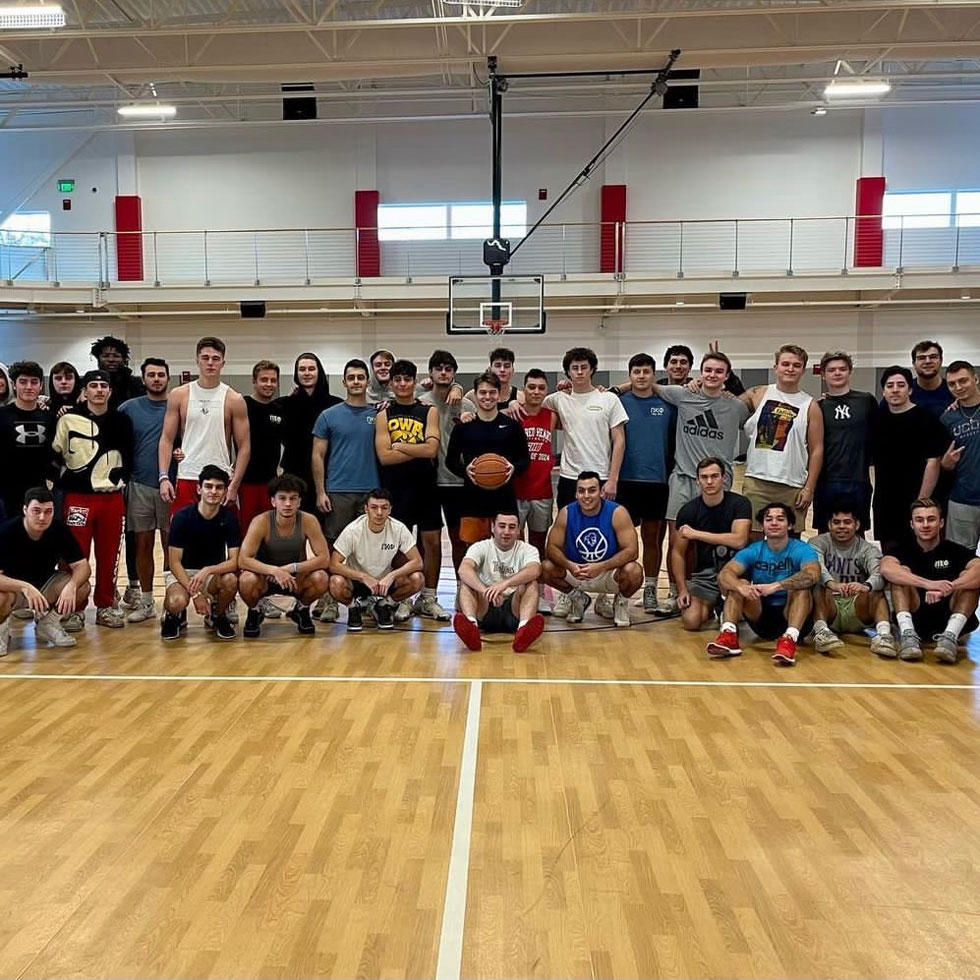 Members of Pi Kappa Phi at a brotherhood event. In athletic wear, playing basketball