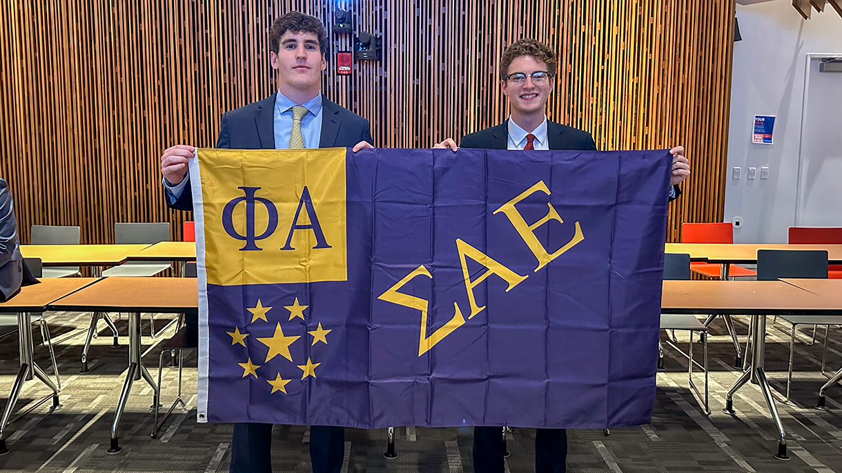 two men holding a sigma alpha epsilon flag