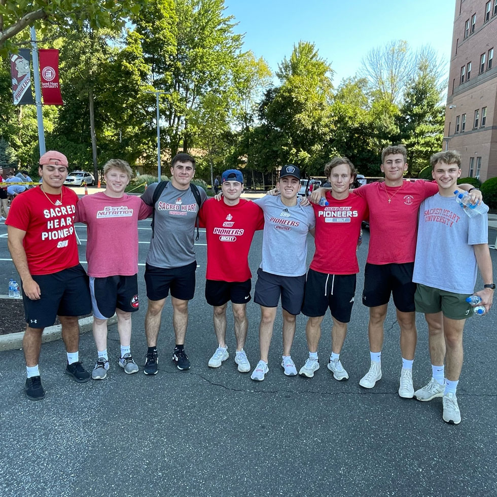 Members of Sigma Chi wearing Sacred Heart University gear and posing for photo
