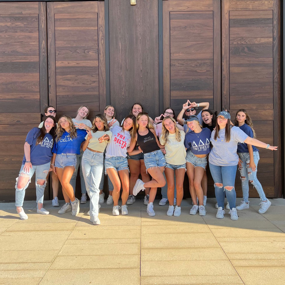 Members of Tri Delta posing for a photo in front of the chapel doors on main campus