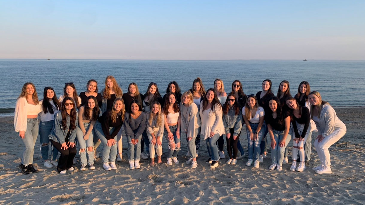 Members of Tri Delta on the beach during sunset posing for photo
