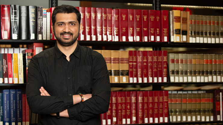 Man smiling in front of shelves of books