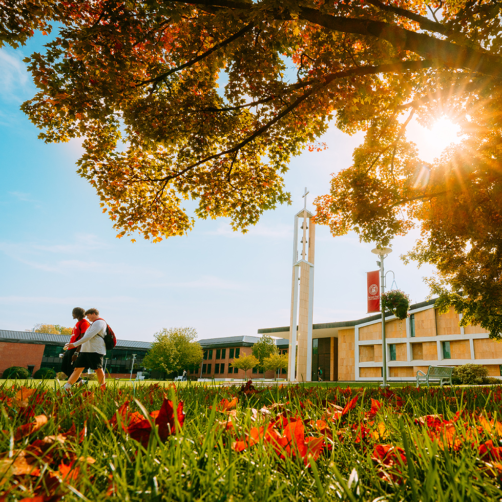 two college students walking on a campus quad in fall