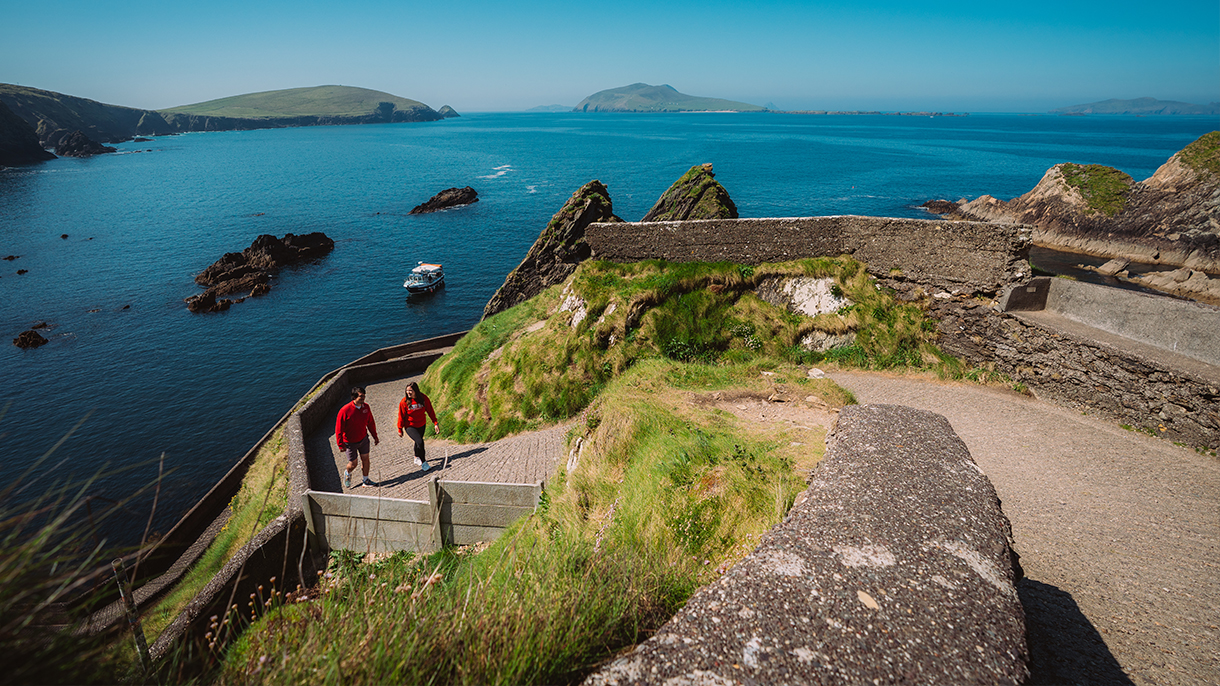 two people walk along a coastal path
