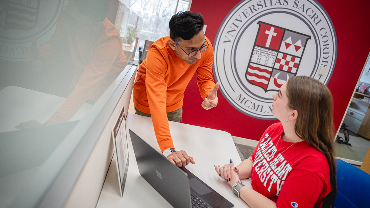 two people talking over a laptop