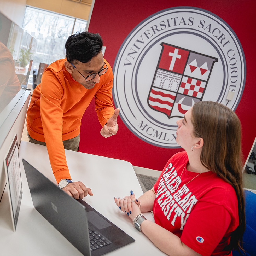 two people talking over a laptop