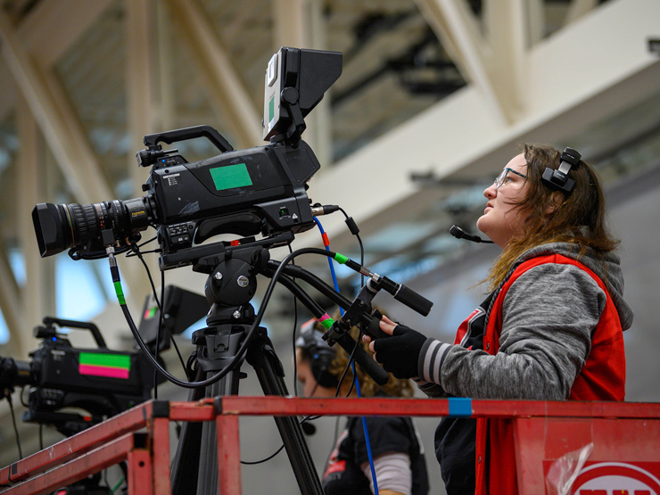 Student operating camera at basketball game