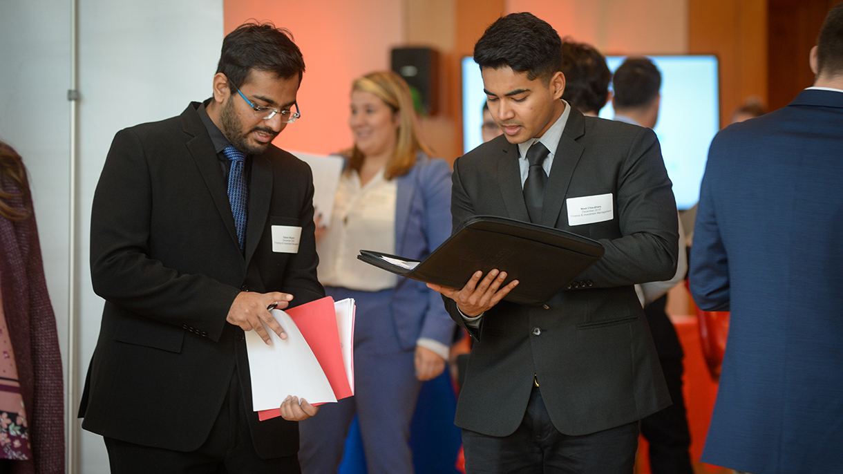 Two people looking in folders at a career fair