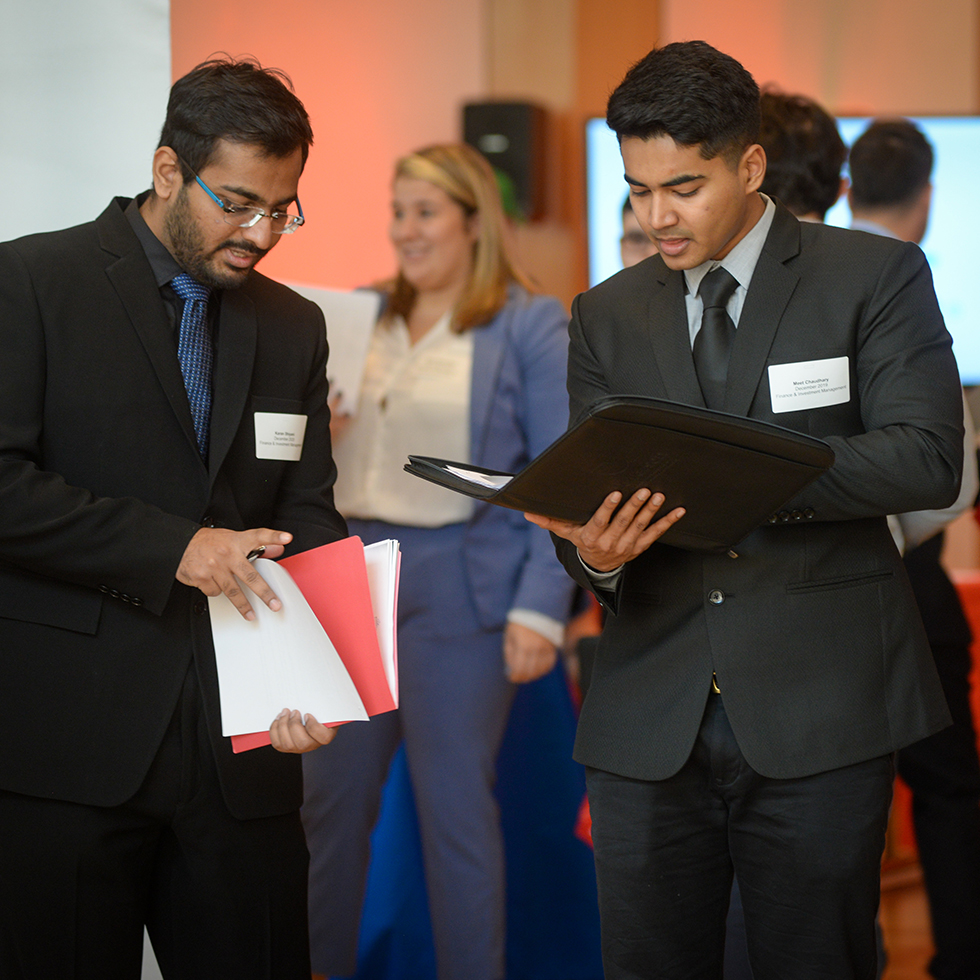 Two people looking in folders at a career fair