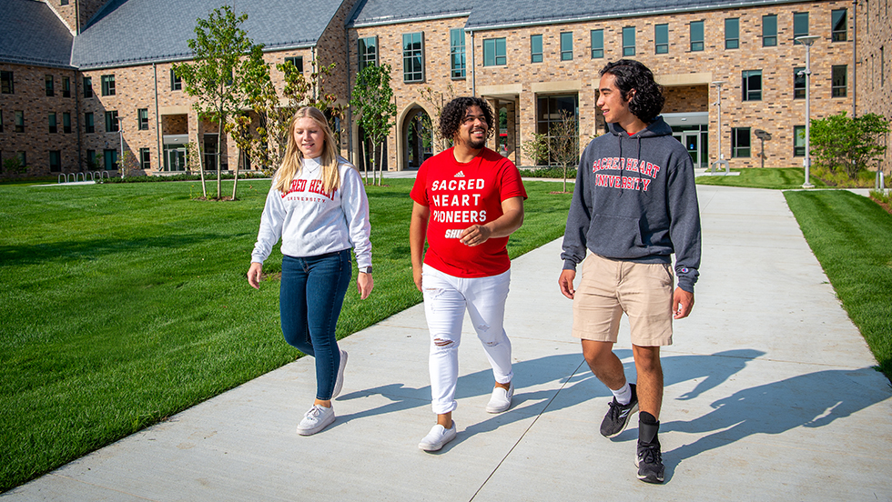 three college students walking by a dorm