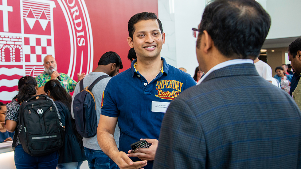 A college student talking to a professor at an open house