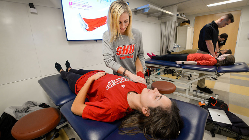 Physical Therapy students checking out patients on table in lab