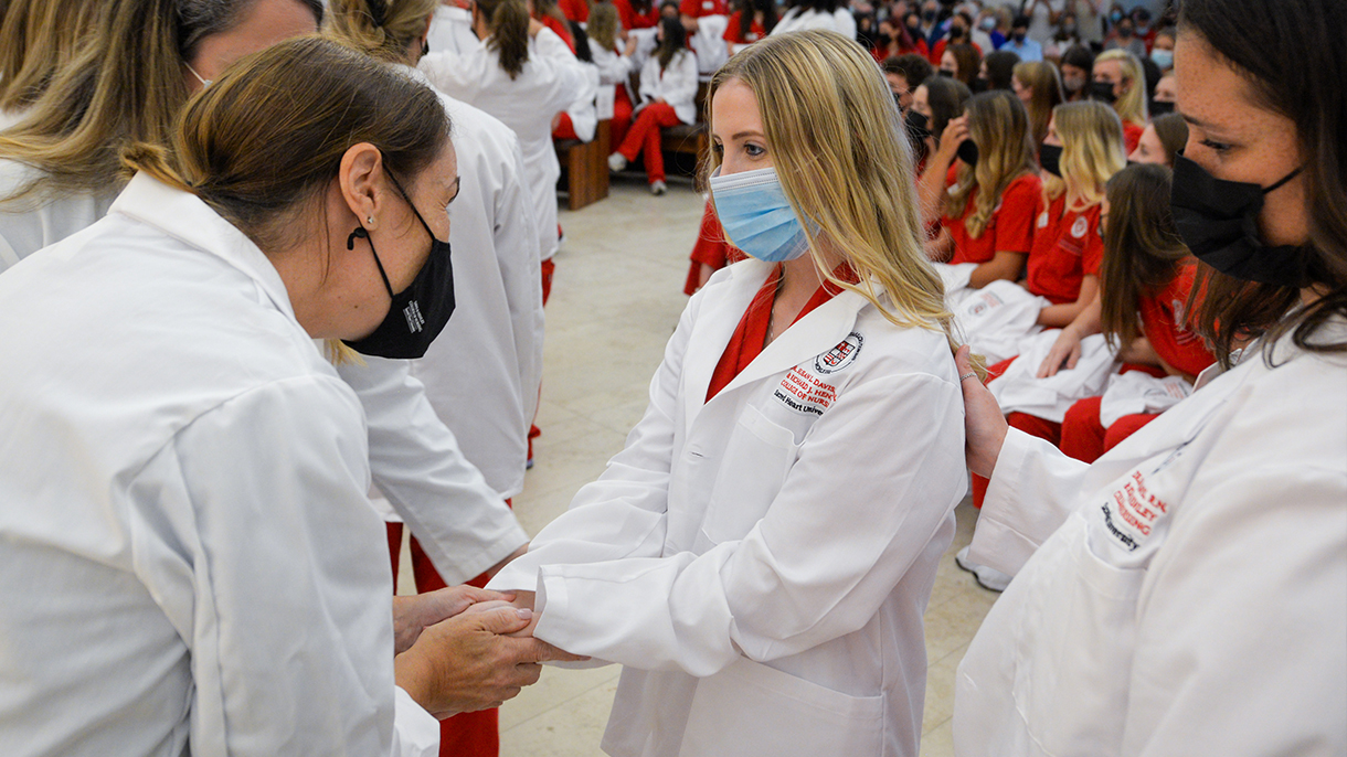 nursing professor blessing the hands of a student