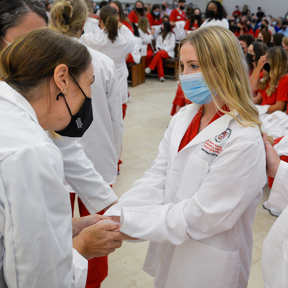 nursing professor blessing the hands of a student