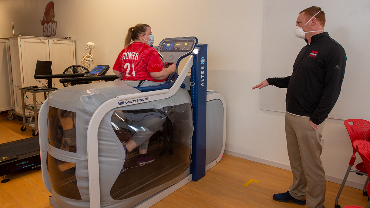 Woman being instructed by an exercise scientist on an anti-gravity treadmill