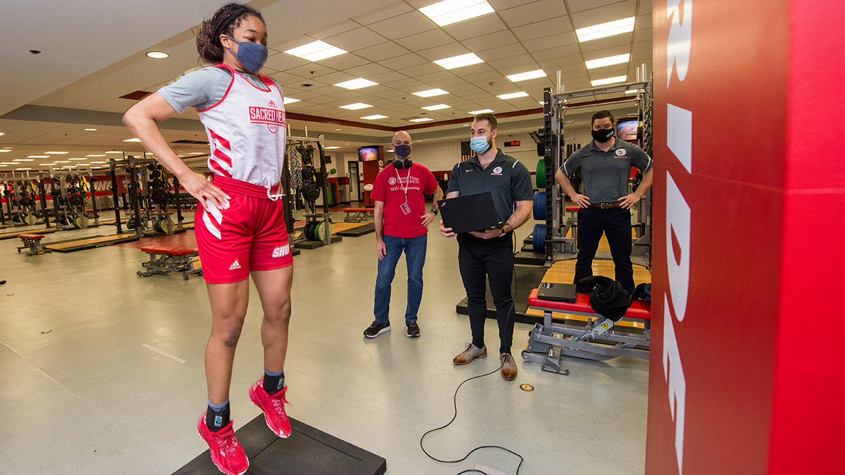 exercise scientists working with a basketball player to measure jump height
