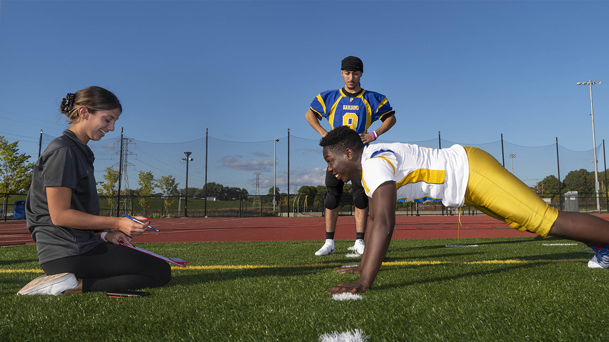 A woman analyzes the exercise routine of a football player