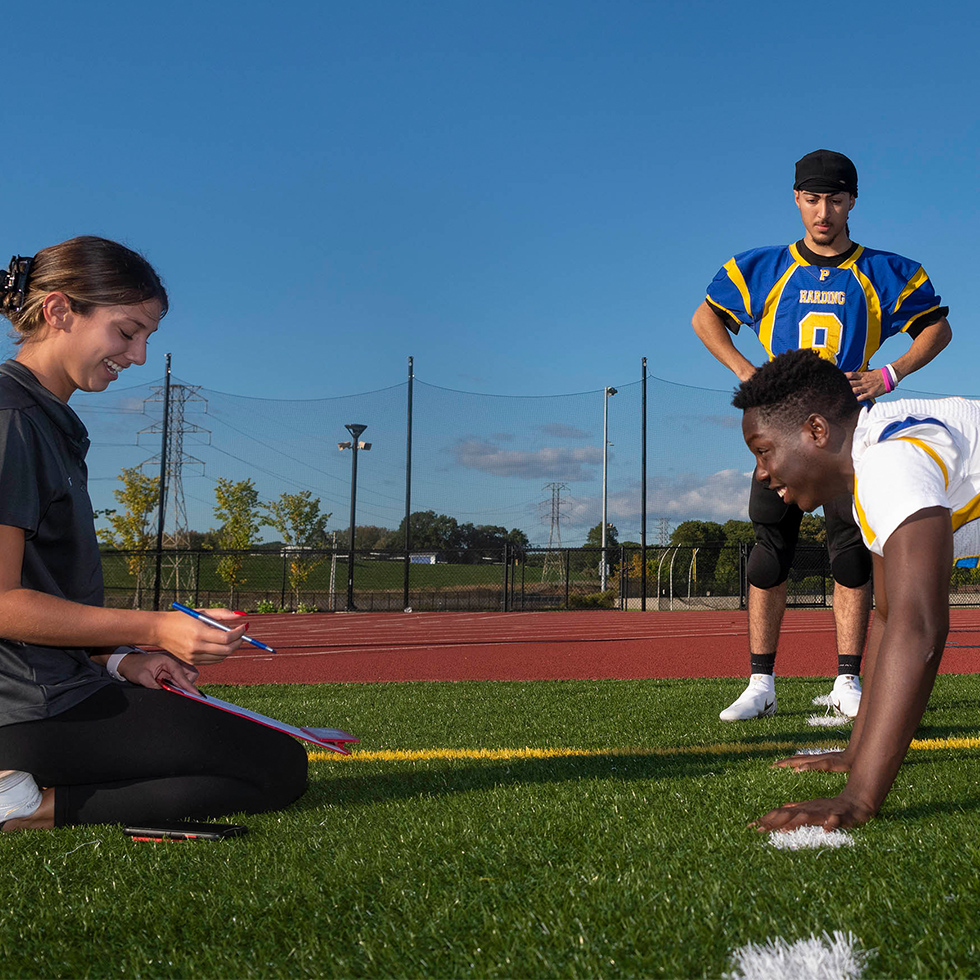 A woman analyzes the exercise routine of a football player