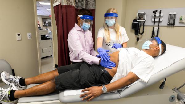 physician assistant professor and student examine a client