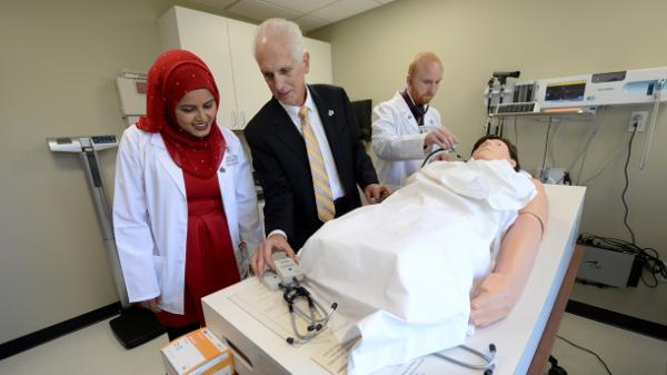 professor and students examine a medical manikin