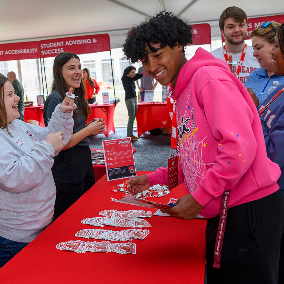 College open house with students and parents laughing at an information table