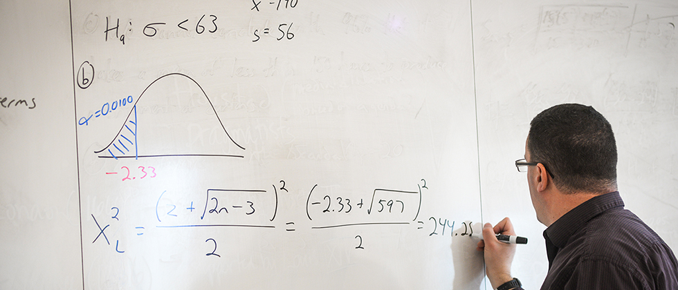 Professor solving a math equation on a white board