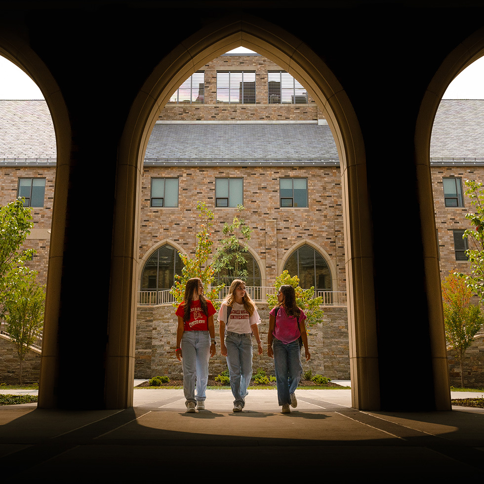 three people walking under an archway