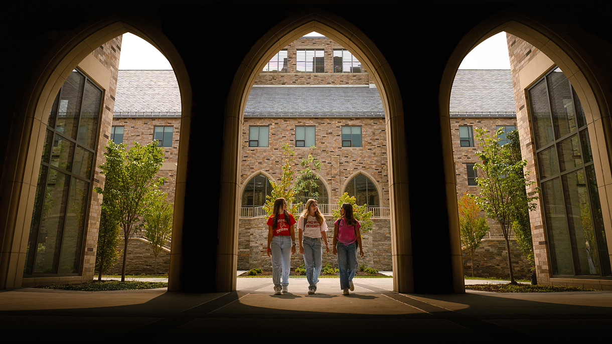 three people walking under an archway