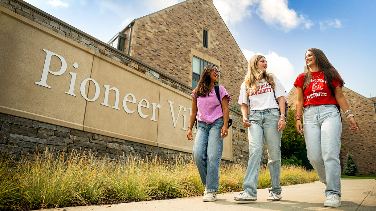students walking by Pioneer Village sign