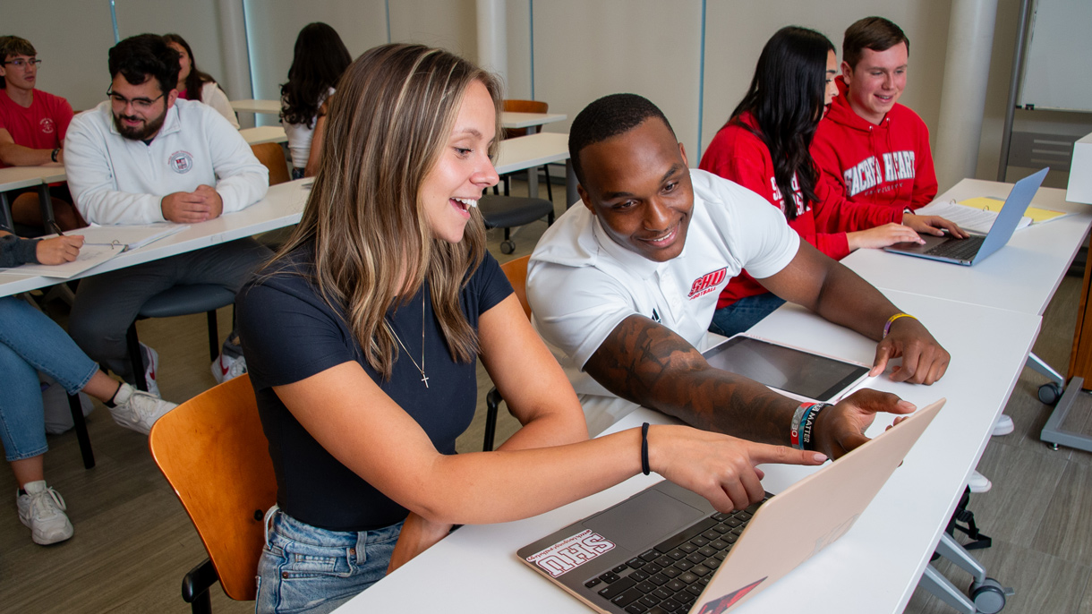 Students working together on laptop in class
