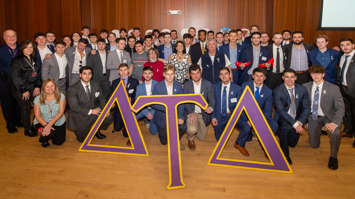 Delta Tau Delta and staff behind Delta Tau Delta greek letters