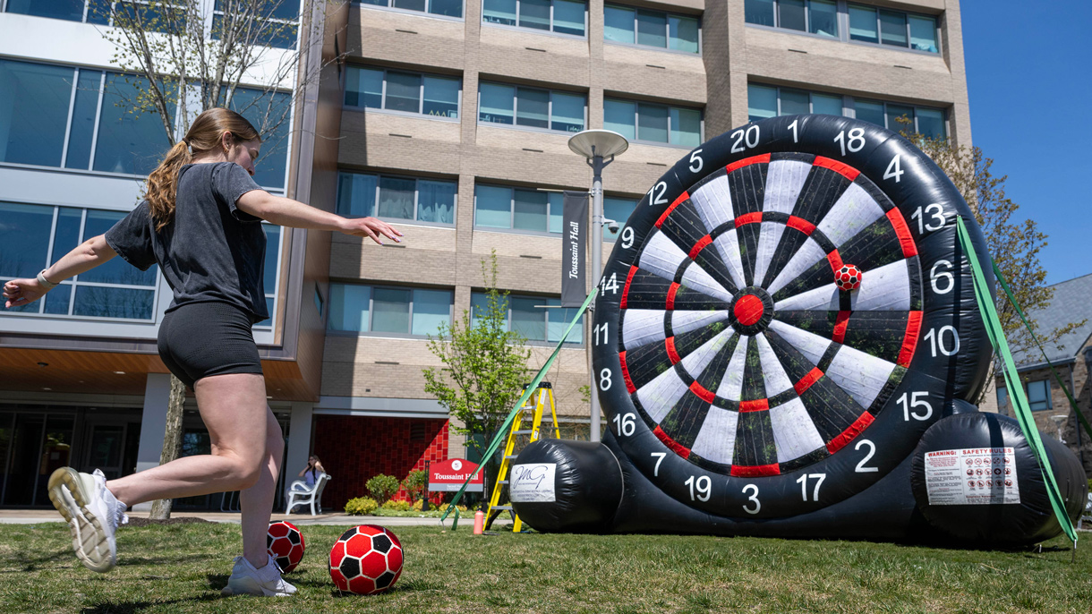 Student kicking soccer ball onto a sticky dart board