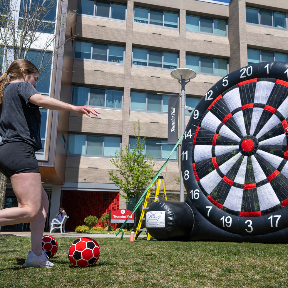 Student kicking soccer ball onto a sticky dart board