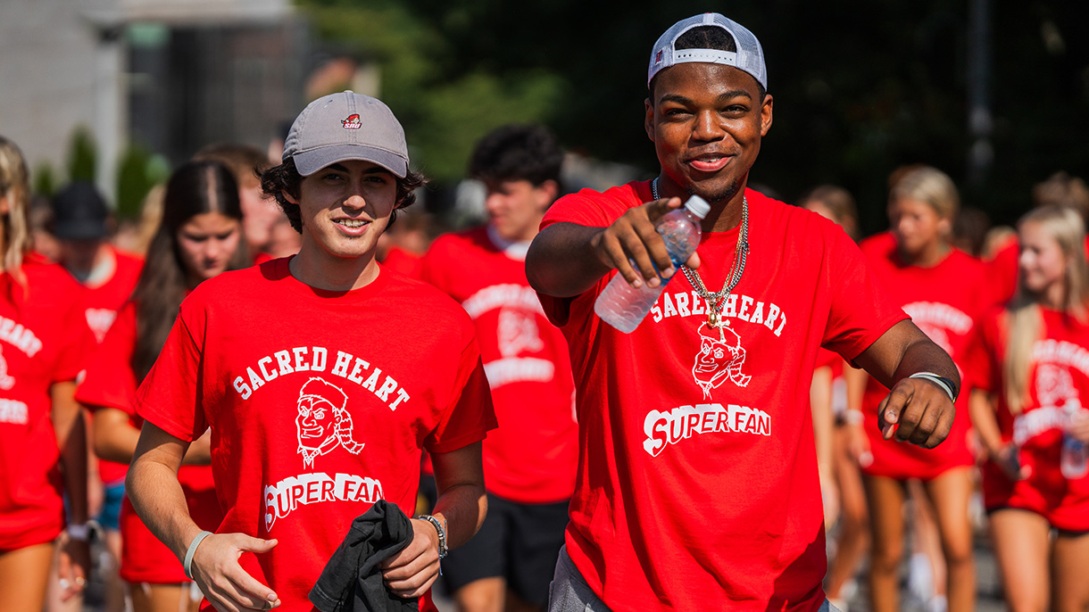 two people in SHU-branded t-shirts posing for a photo