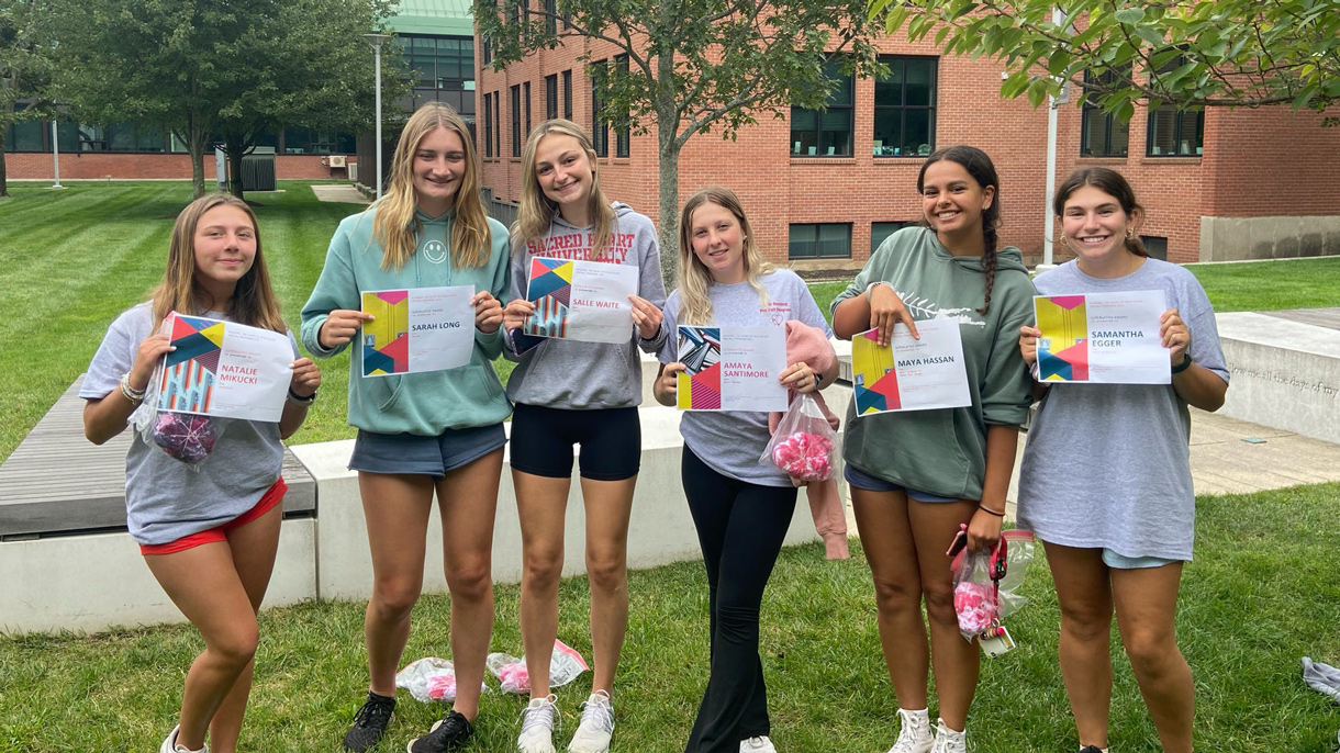 Group of students holding up paper