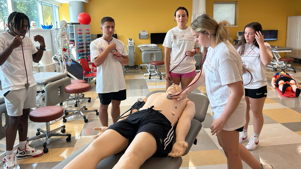 Students listening to manikins heartbeat