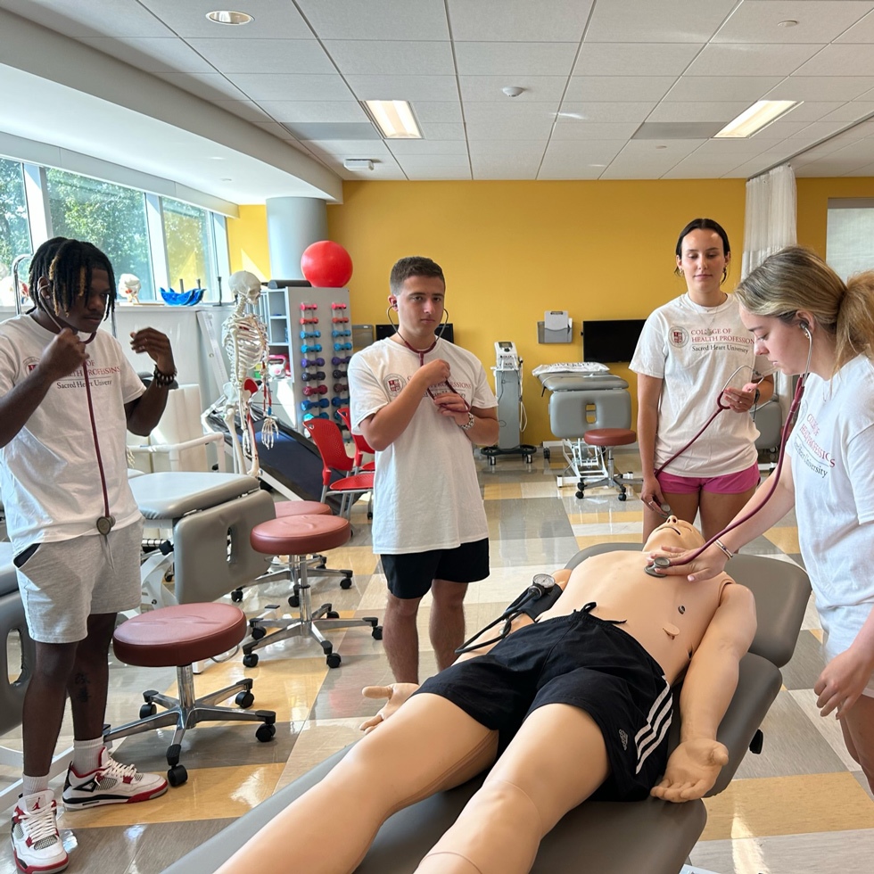Students listening to manikins heartbeat