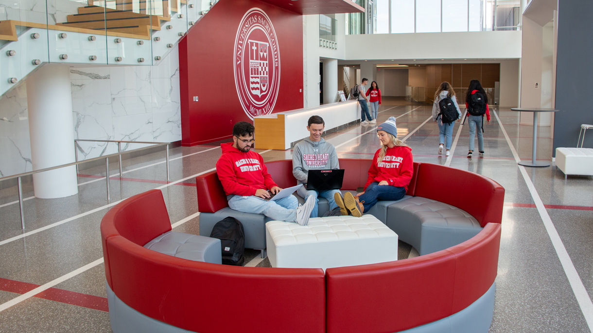 Students relaxing and on laptops in atrium