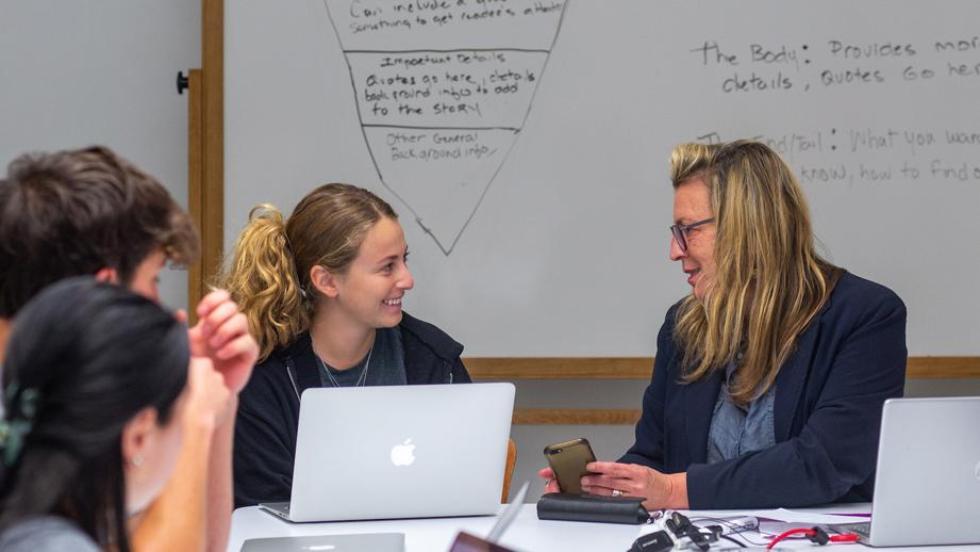 Students talking to professor in classroom