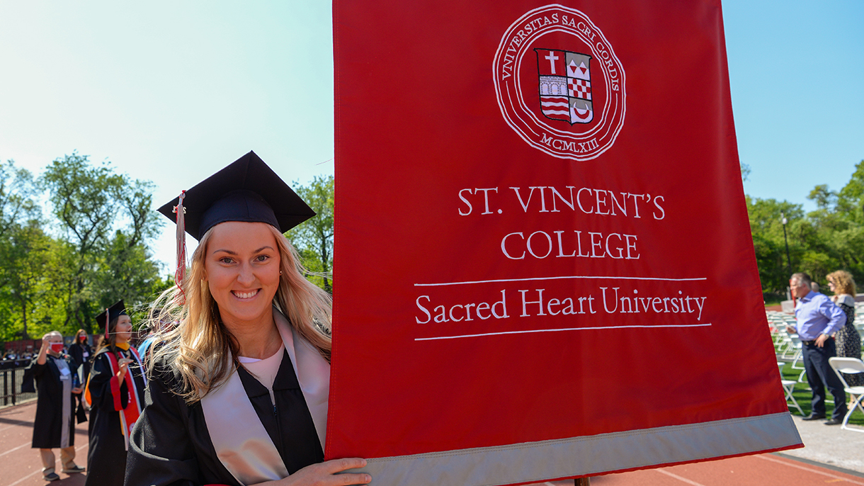 A graduate holds the St. Vincent's College banner
