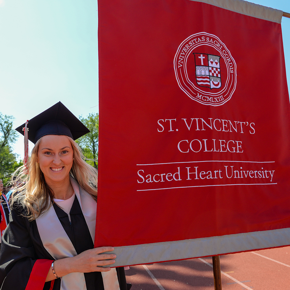 A graduate holds the St. Vincent's College banner