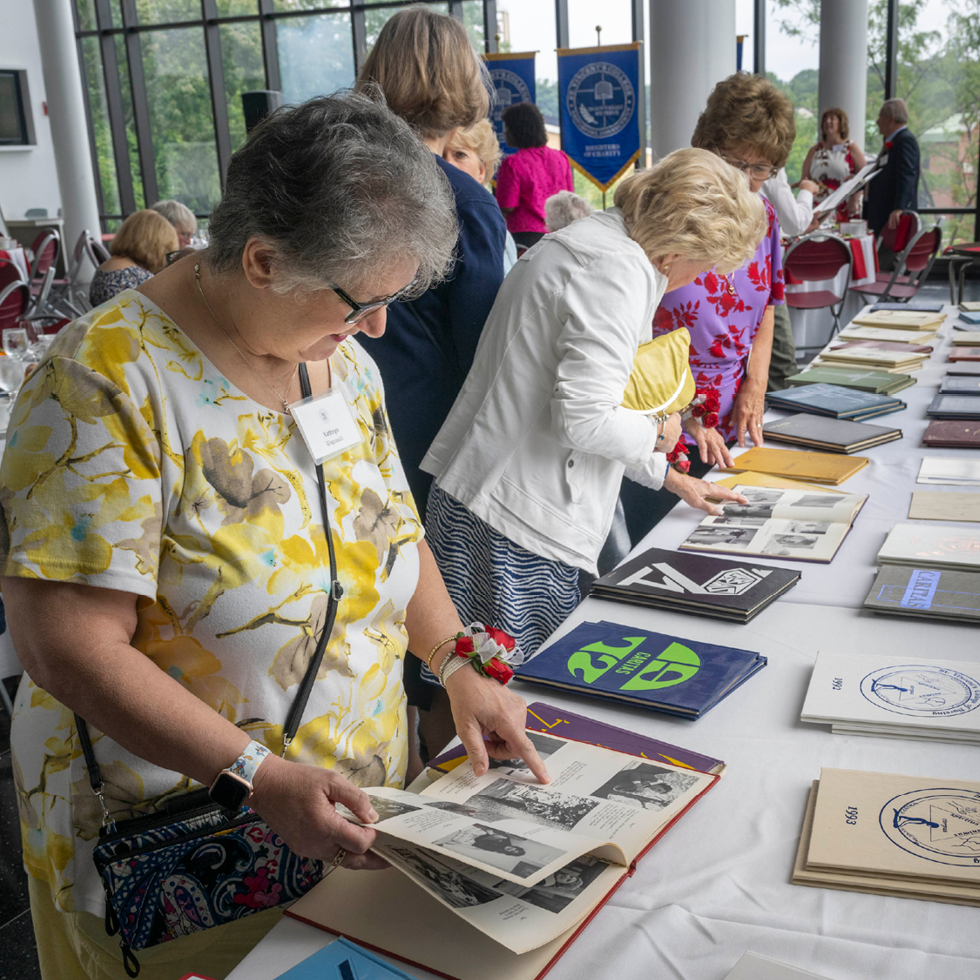 Women reading old Sacred Heart yearbooks