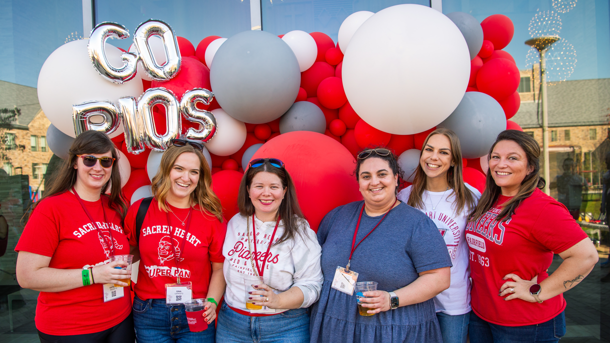 Group of alumni in front of balloons at Homecoming