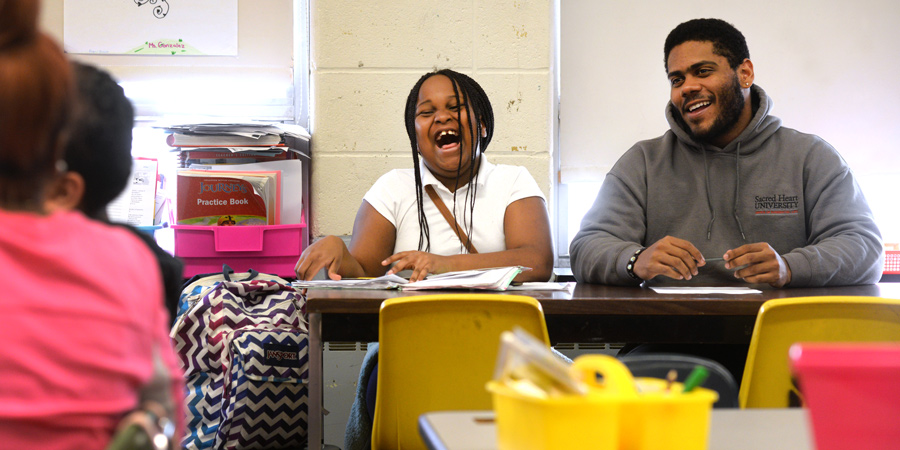 SHU student laughing with child in classroom